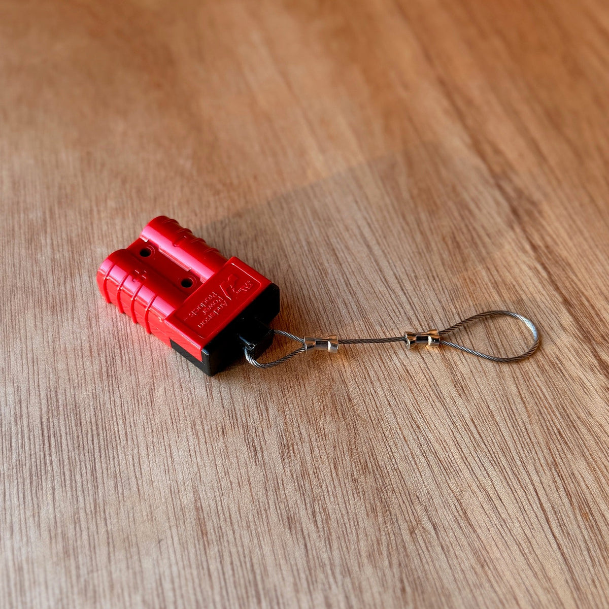 Red Anderson-style plug fitted with a black TPU dust cover and stainless steel wire tether