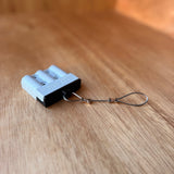 White Anderson-style plug fitted with a black TPU dust cover and stainless steel wire tether